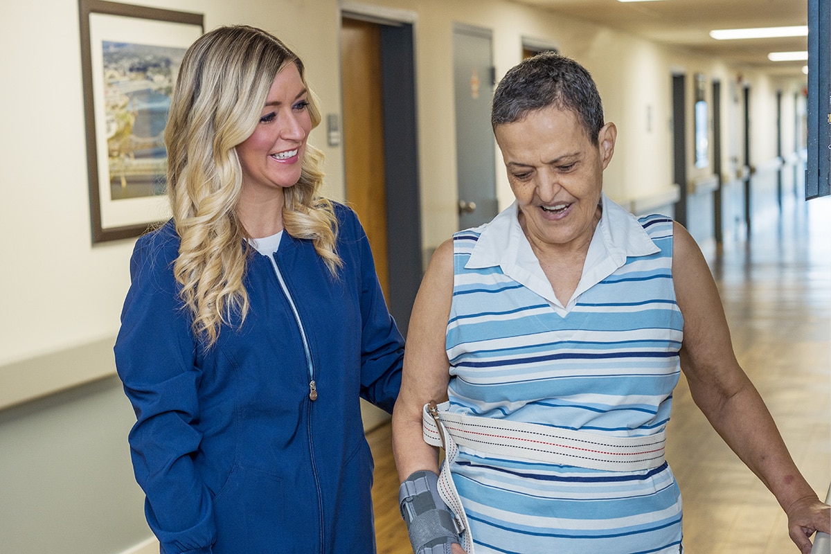 Nurse helping a resident in the hallway at Norwood Towers